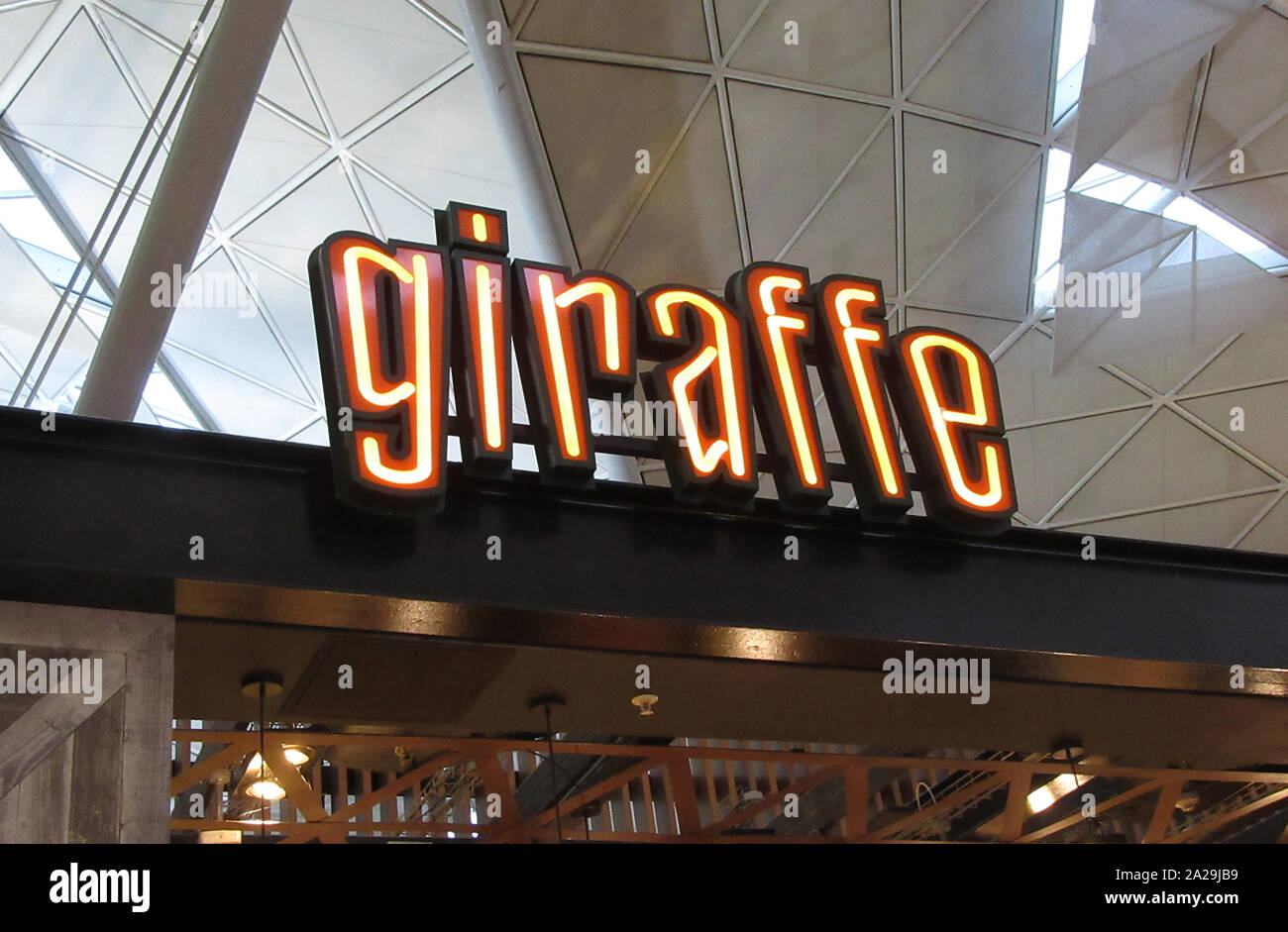 La giraffa di digital signage e logo che si vede presso il loro ristorante a Londra Stansted Airport. Foto Stock