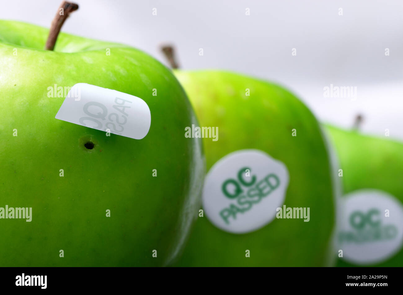Foro in apple nascosto da QC PASS adesivo, che illustra il fallimento nel controllo di qualità Foto Stock