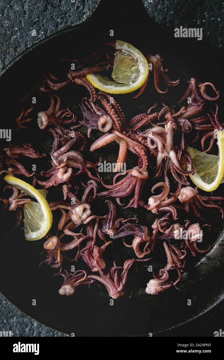Calamari alla griglia di tentacoli di calamari con limone in ghisa pan. Close up, cibo sfondo, vista dall'alto Foto Stock