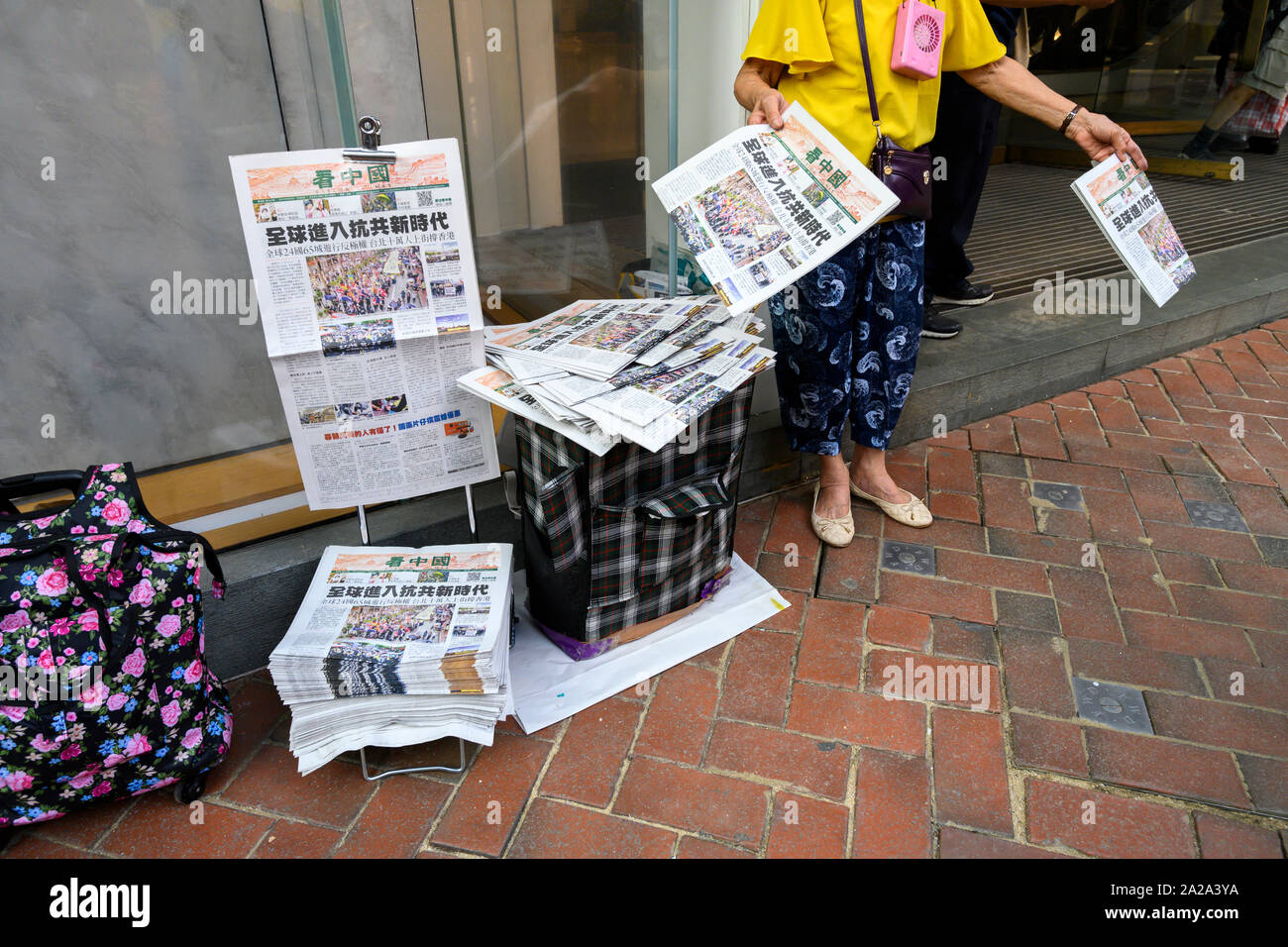 Il 2 ottobre 2019. Hong Kong riprende il business la mattina dopo violente proteste il 1 ottobre 2019. Una donna vende quotidiani rivestimento padiglione la Giornata nazionale di protesta. Foto Stock