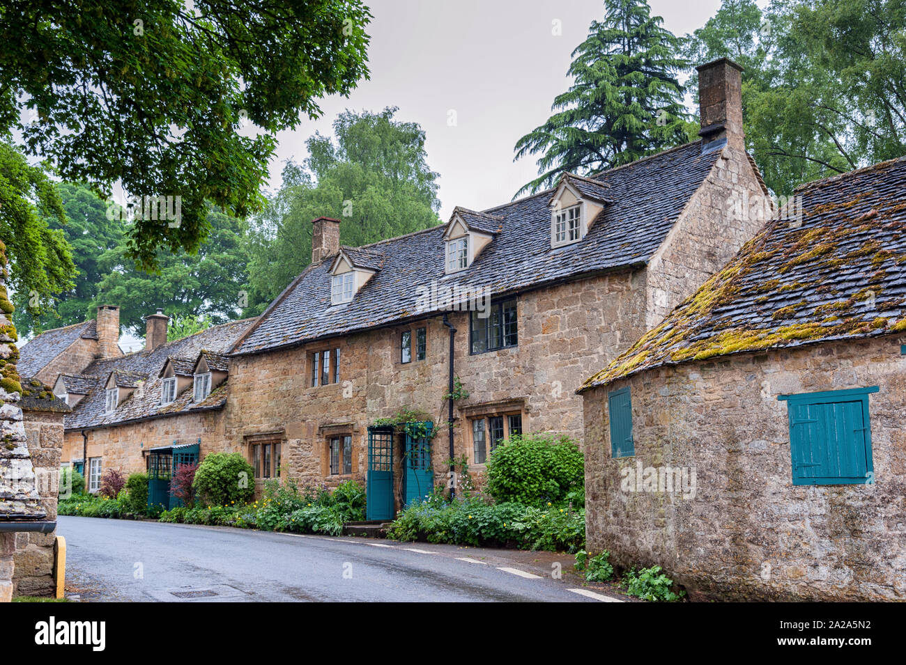 Tipici cottage grazioso con piante rampicanti con giallo Cotswold pareti in pietra calcarea e tetto in ardesia con giardino delle rose in Snowshill, Cotswolds Inghilterra Foto Stock