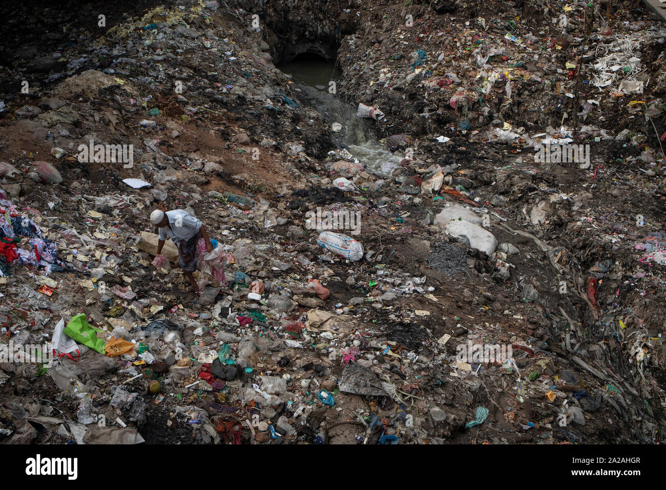 Un uomo sceglie di plastica per il riciclo come l acqua inquinata da scarichi nel fiume Buriganga nella capitale Dhaka, Bangladesh, 27 aprile 2019. Foto Stock