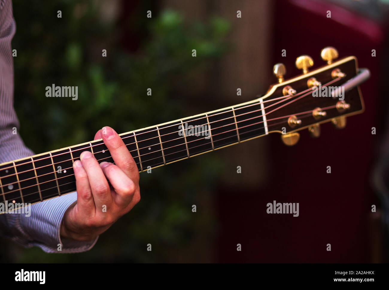 Chitarra con un uomo maschio del mani a suonare la chitarra sulla parete in legno sfondo, elettrico o una chitarra acustica con luce naturale. Concetto di ragazzi ragazzi band Foto Stock