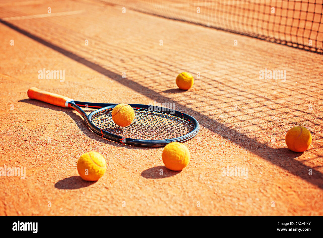 Racchetta da Tennis e le sfere sul terreno nell'ombra della rete Foto Stock