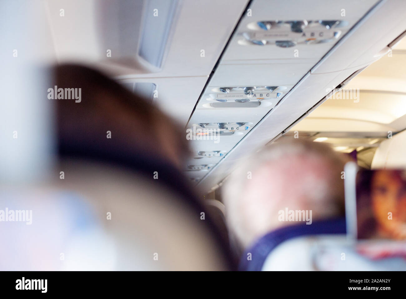 Interior shot di un aereo di linea di passeggeri/velivolo, con i passeggeri seduti sui sedili, con focus principale sul tetto di controlli e pulsanti. Foto Stock