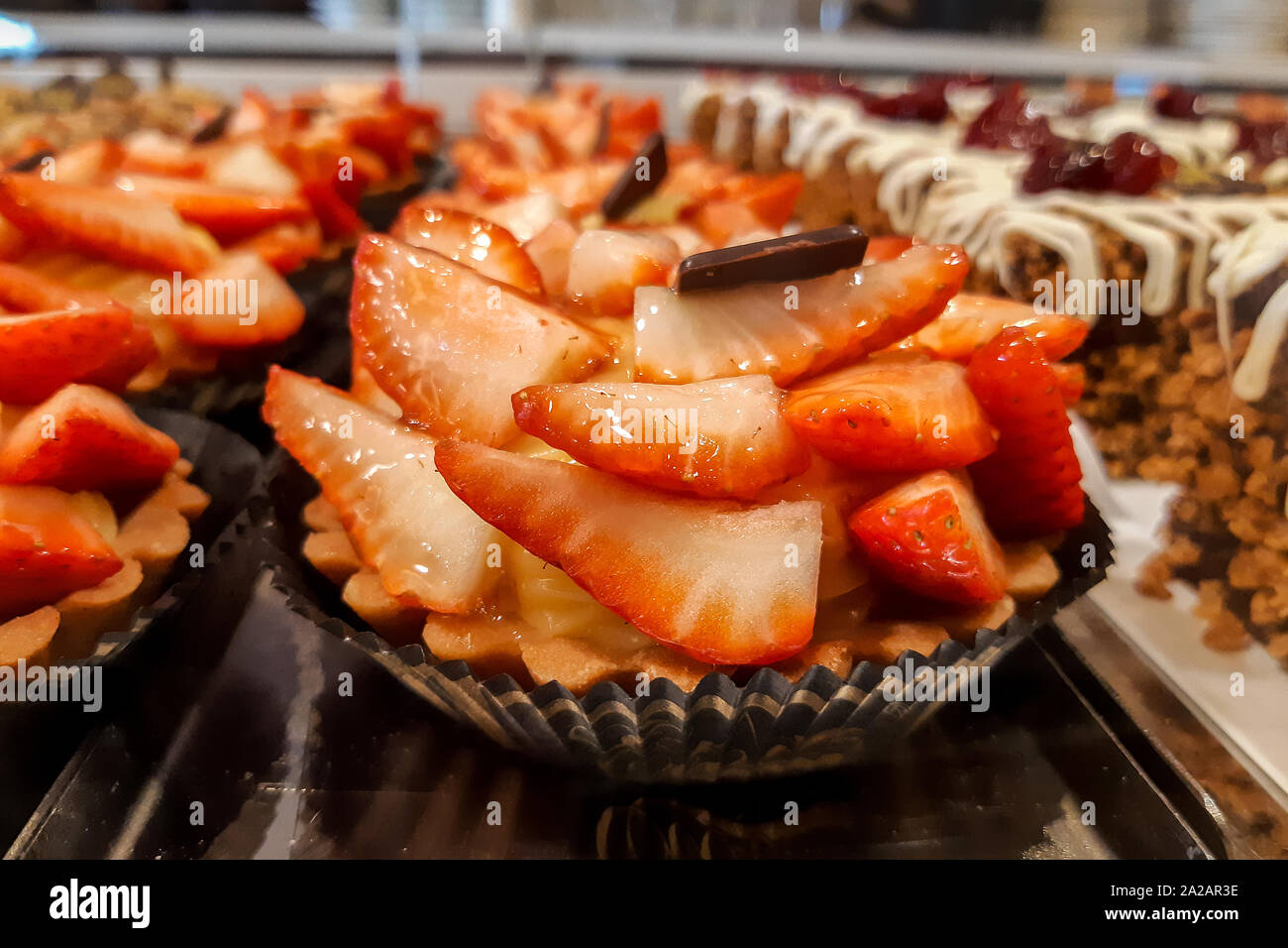 Coppa di fragole torta e panna montata decorata con cioccolato sulla piastra marrone Foto Stock