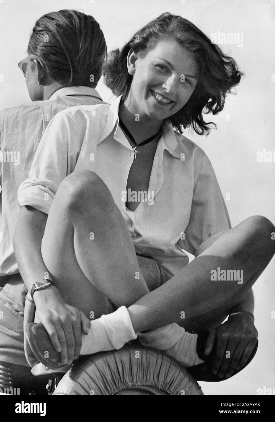 Una giovane coppia godendo l'estate. Essi prendono un viaggio sullo scooter. Egli unità, si siede nella parte posteriore sulla ruota di scorta. Foto Stock