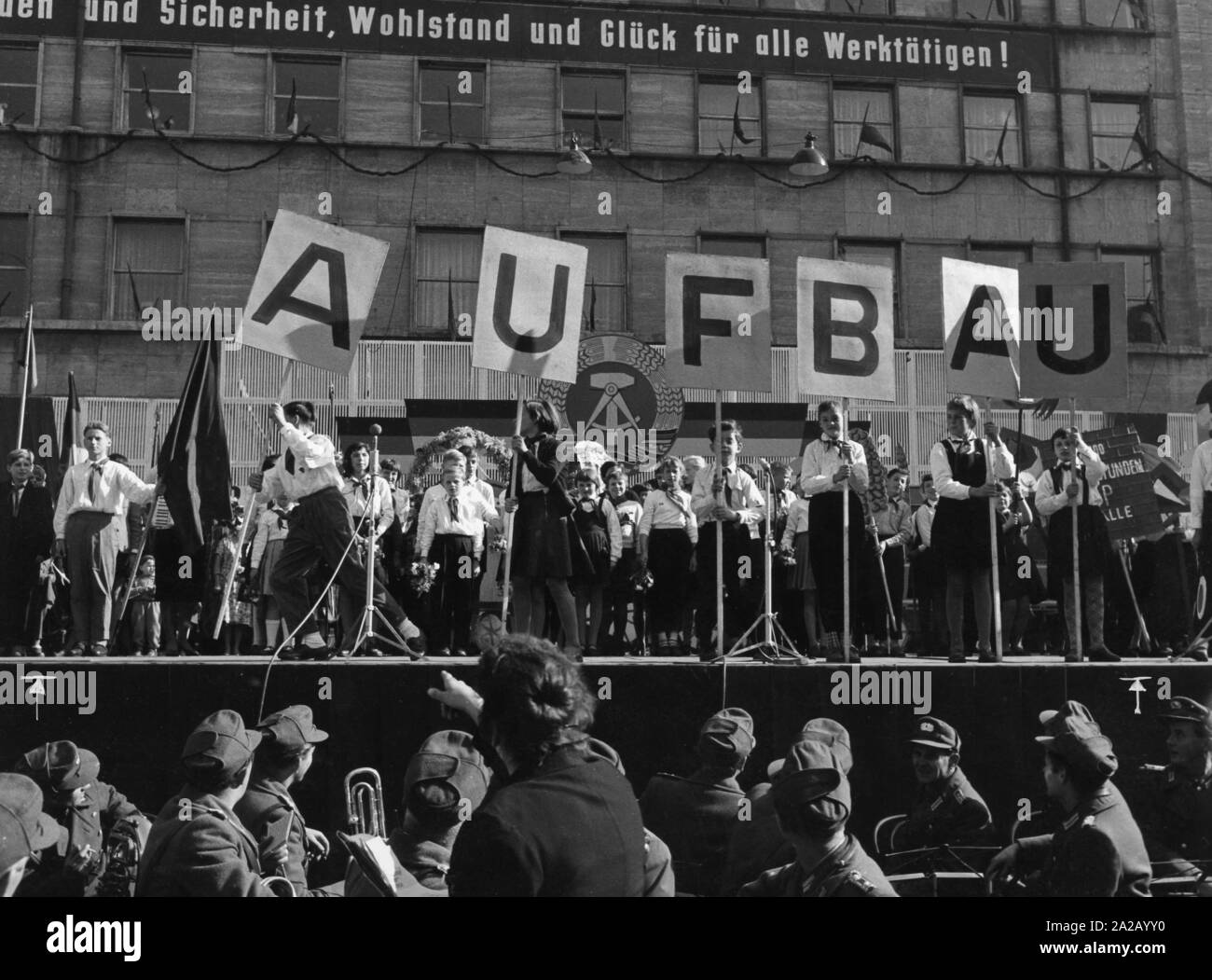Le grandi celebrazioni a marchio "dieci anni della RDT " svolgerà a Halle e a Berlino Est. La foto mostra un evento di Halle. Pionieri tenere i segni che compongono la parola 'costruzione'. Un logo sulla costruzione in background dice " Pace e sicurezza, prosperità e felicità per tutti lavorano persone!!!!" Foto Stock