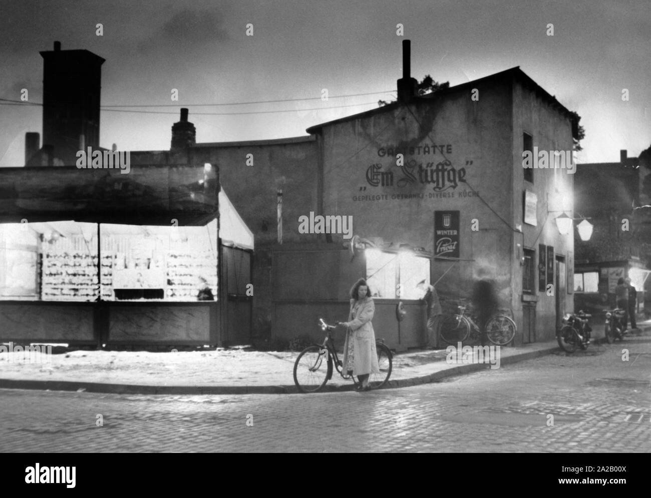Una scena di strada nel post-guerra in Germania (Colonia?) di notte. Nel centro è una donna con la bicicletta non datata (foto). Foto Stock