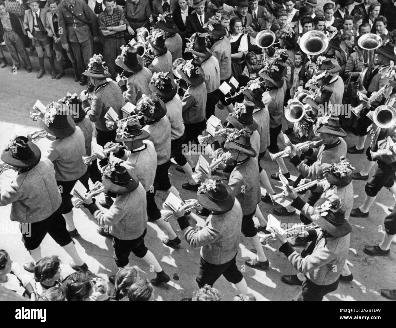 Una banda tirolese in costumi tradizionali si muove attraverso le strade accompagnati da spettatori. Foto non datata, probabilmente negli anni cinquanta. Foto Stock