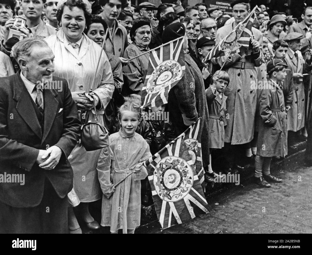 Una grande folla di seguaci della monarchia britannica ha raccolto sul ciglio della strada. Le bandiere rappresentano la regina Elisabetta II. L'occasione è stata la visita del Presidente federale Theodor Heuss a Londra. Foto Stock
