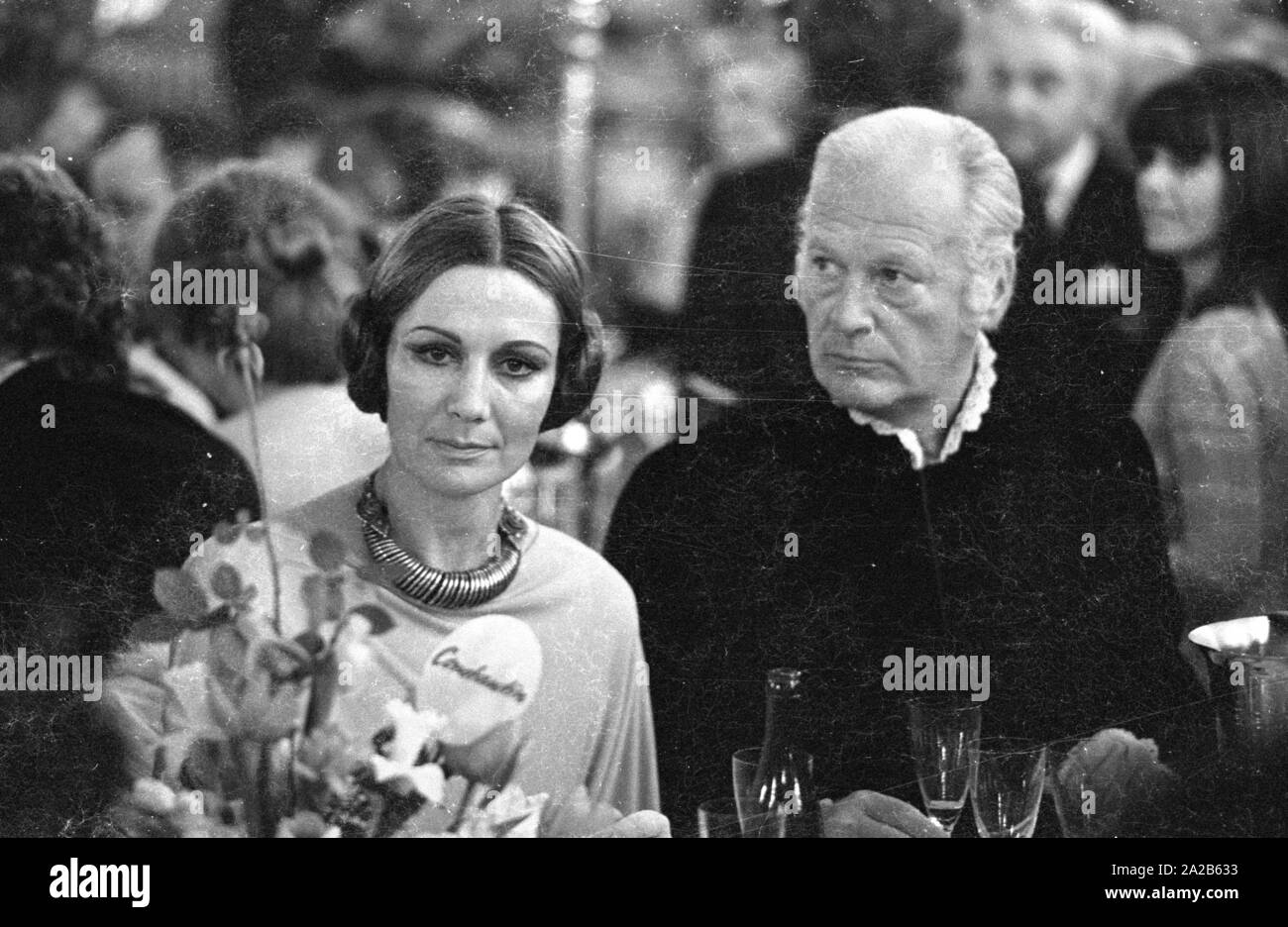 Cagliata Juergens con la moglie Simone presso il Film palla in Monaco di Baviera, nel Bayerischer Hof. Simone indossa i suoi capelli arrotolato. In primo piano è un mazzo di fiori sul tavolo con una nota su di esso, recanti il marchio Constantin. Ci sono bicchieri di champagne sul tavolo. Foto Stock