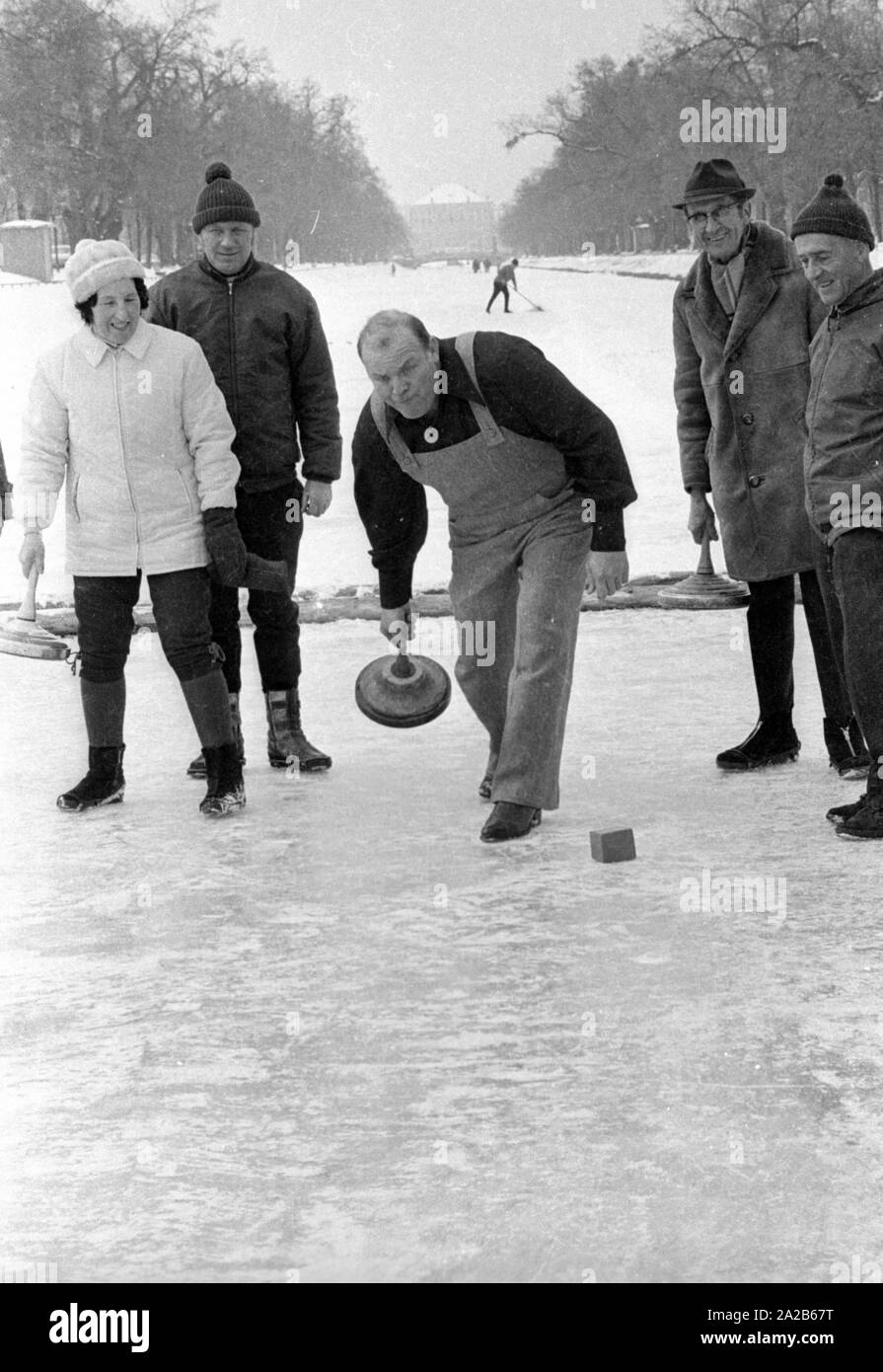 Dan Blocker, che svolge il ruolo di Hoss Cartwright nella serie televisiva Bonanzna, qui al centro, con una borsa di ghiaccio nella sua mano mentre il curling sul canale di Nymphenburg. Attorno a lui sono alcuni giocatori. Foto Stock