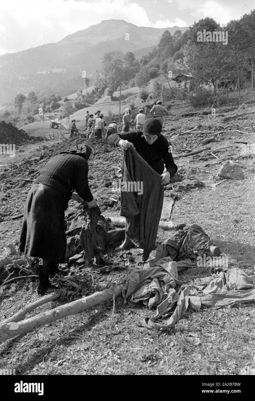 Due donne per vestirsi. Essi sono in piedi su una pendenza che è scivolato nella tempesta in Italia. La tempesta ha devastato la città di Loveno, la Valcamonica e Boario Terme in provincia di Brescia in Lombardia. Foto Stock