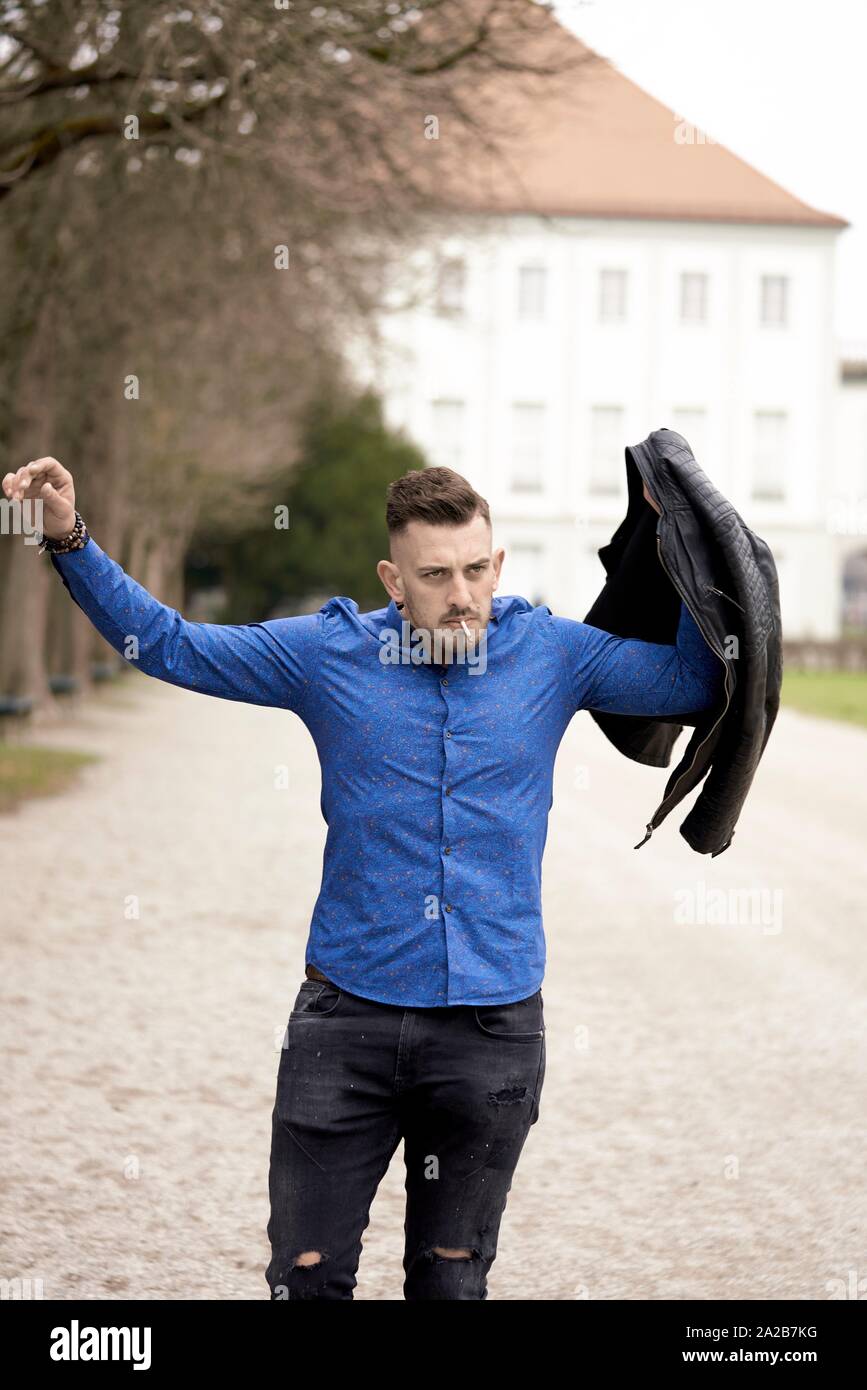 Uomo in camicia azzurra mettendo nero su giacca di pelle, Monaco di  Baviera, Germania Foto stock - Alamy