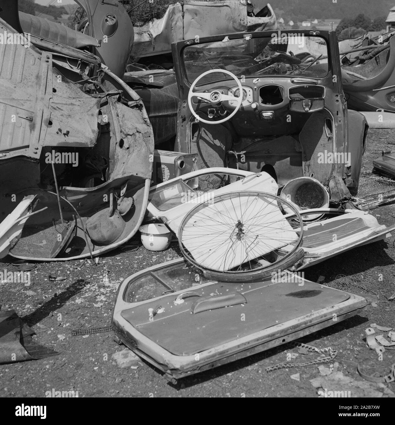 Auto rottamate su un junkyard. Qui può essere riconosciuta la parte anteriore di un Maggiolino con il cruscotto e il volante come pure diverse porte e una ruota a raggi di bicicletta. Foto Stock