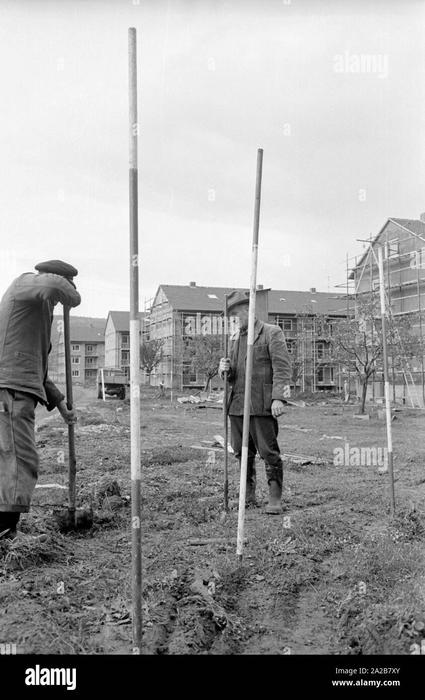 Due uomini stanno effettuando la primal rilievi topografici in preparazione per la costruzione di ulteriori nuovi tenement case. Foto Stock