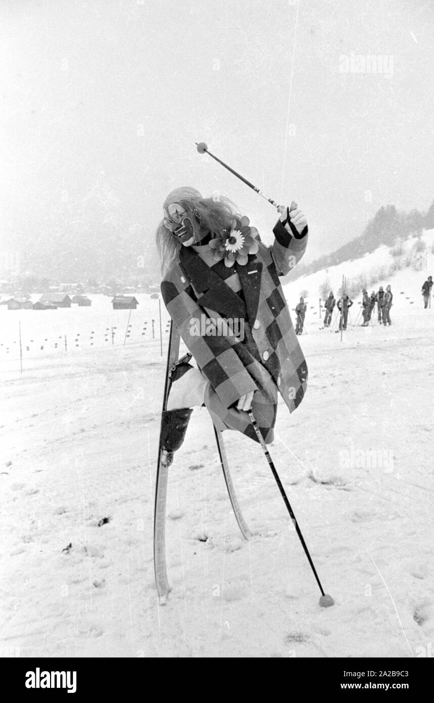 Presso la scuola di sci Garmisch, un clown dà lezioni di sci. La società marker' pubblicizza con striscioni la sua sicurezza attacchi da sci. Foto Stock