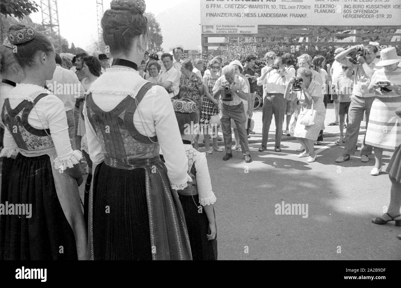 Ragazze in costume di un tradizionale sfilata in costume della Baviera superiore vengono fotografati dai turisti. Foto Stock