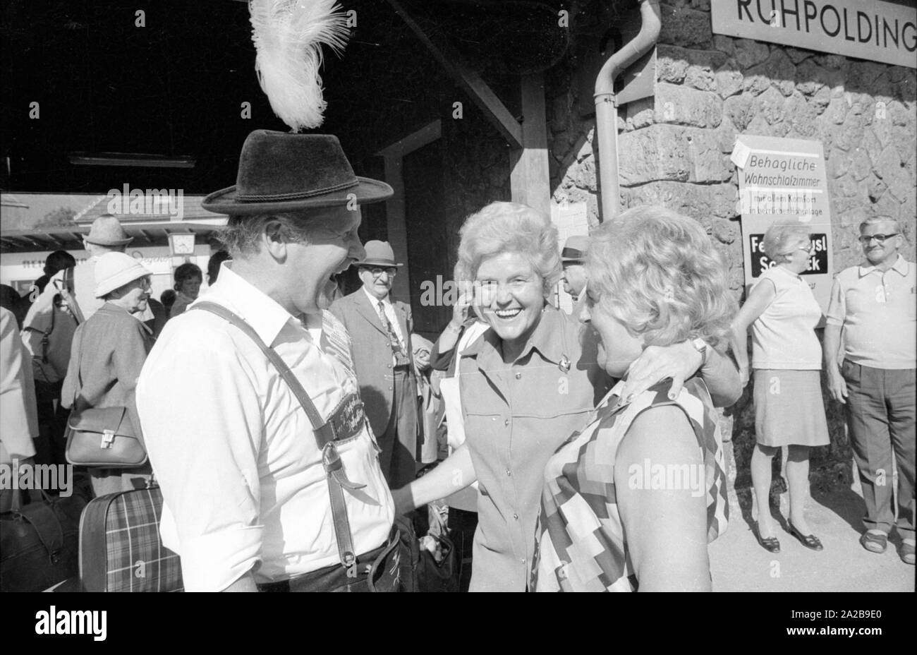 I molti turisti che arrivano con il treno alla stazione ferroviaria del centro termale e della località turistica Ruhpolding . Foto a sinistra: un membro della Gebirgstrachtenerhaltungsverein Miesenbacher Ruhpolding (club per il supporto dei costumi tradizionali delle genti di montagna) in conversazione con due donne. Foto Stock