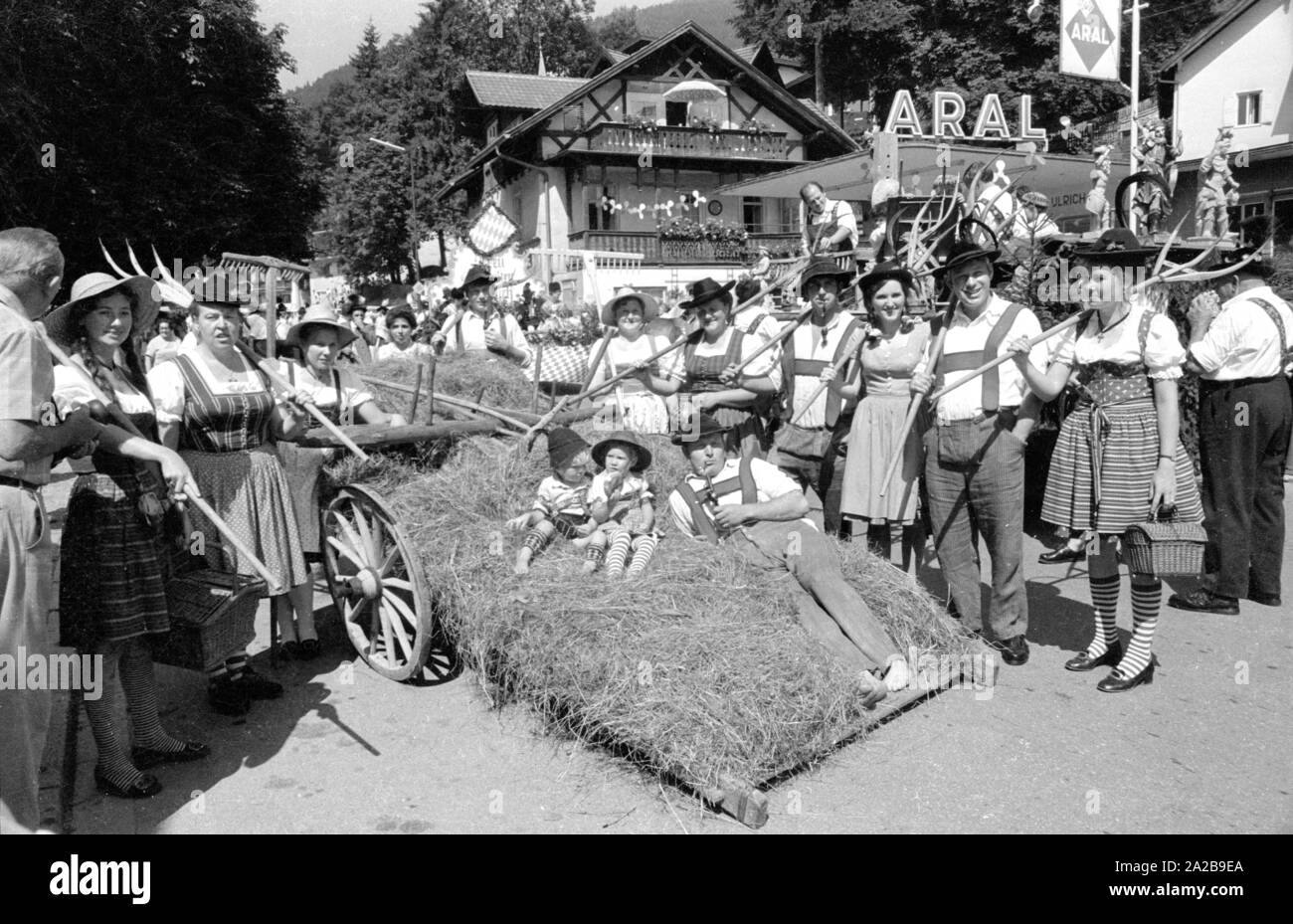 Persone in costumi tradizionali con attrezzature agricole in una sfilata in costume in Alta Baviera. Foto Stock