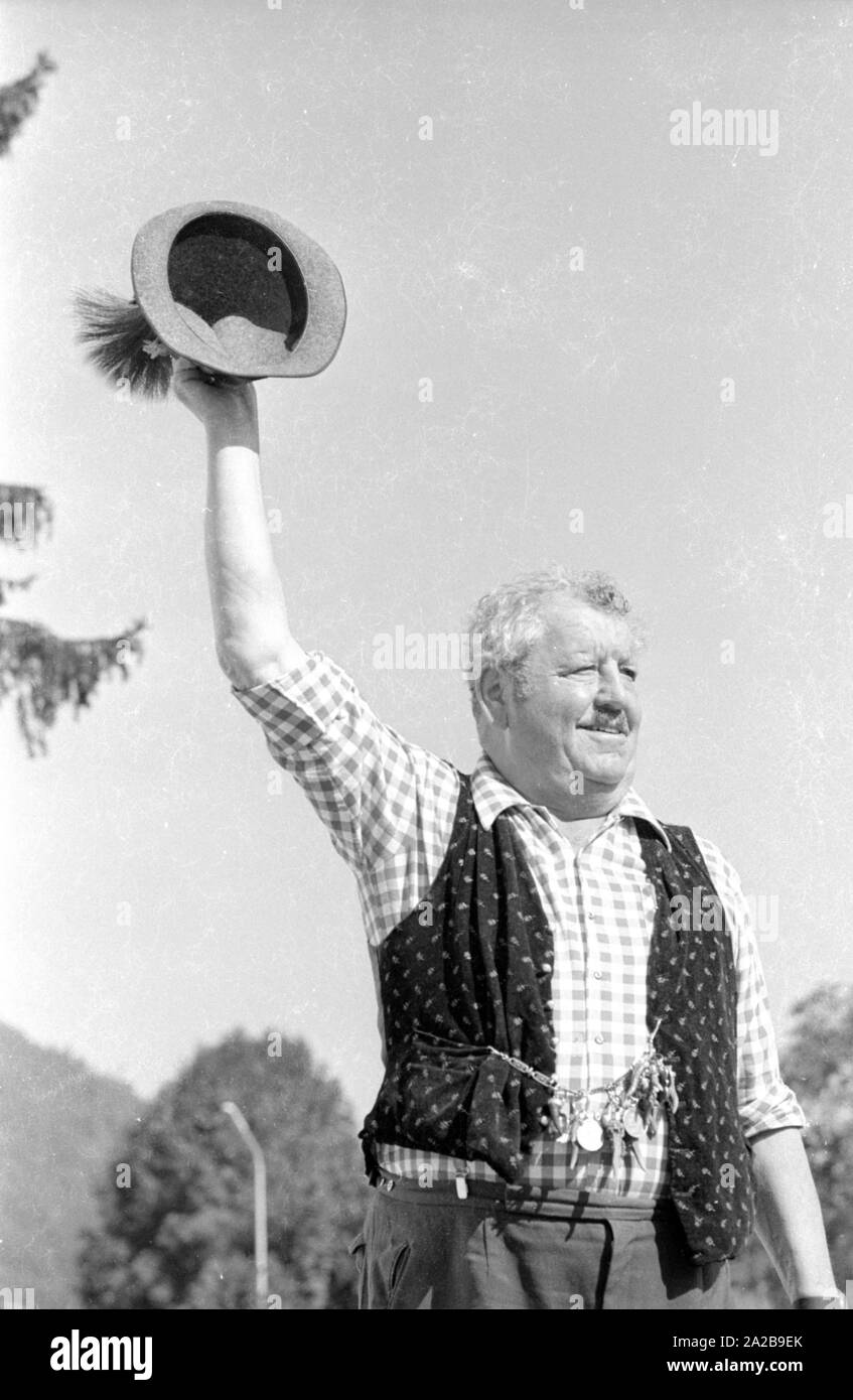 Un uomo in abiti tradizionali solleva il suo cappello nel messaggio di saluto. Foto Stock