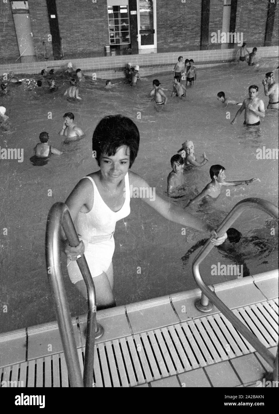Una donna in un bianco costume da bagno entra nel pool. Foto Stock Una donna in un bianco costume da bagno entra nel pool. Foto Stock