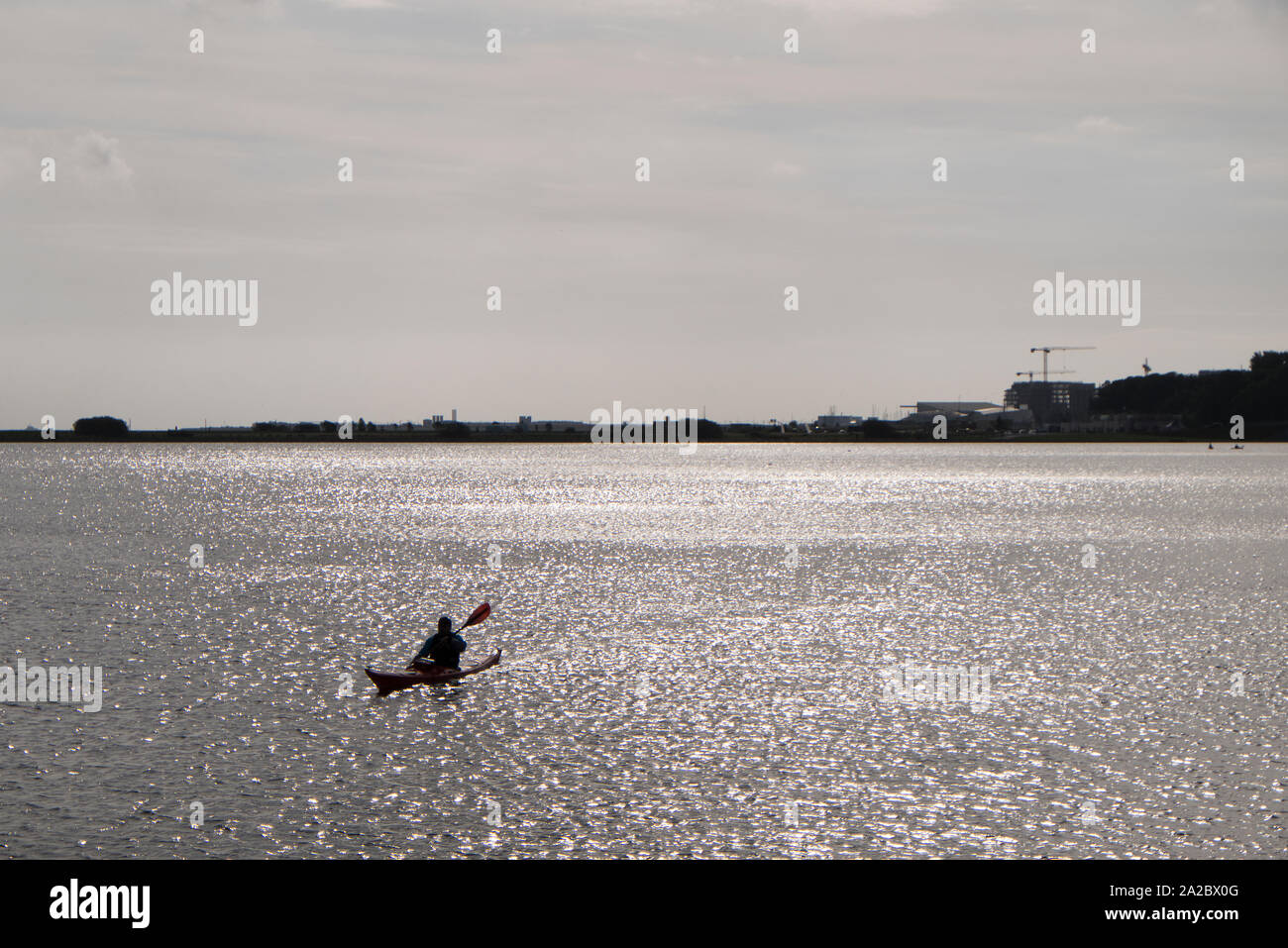 L'uomo kayak in estuario in Kobenhavn di Copenaghen su un nuvoloso giorno di autunno, Danimarca Foto Stock