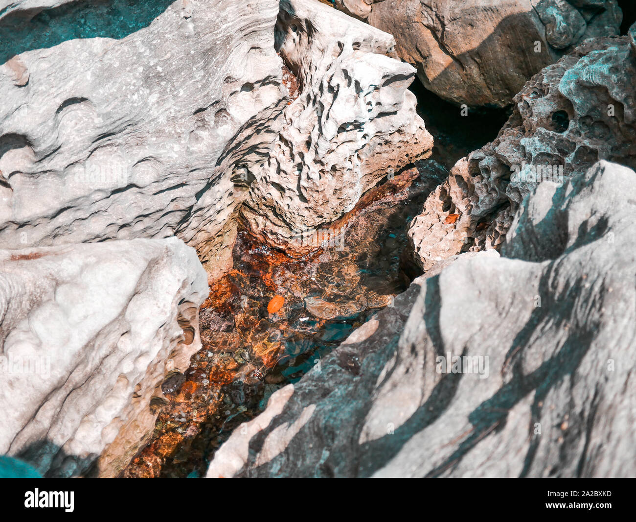 Colorata rock texture di superficie e l'acqua all'oceano naturale in condizioni di luce diurna Foto Stock
