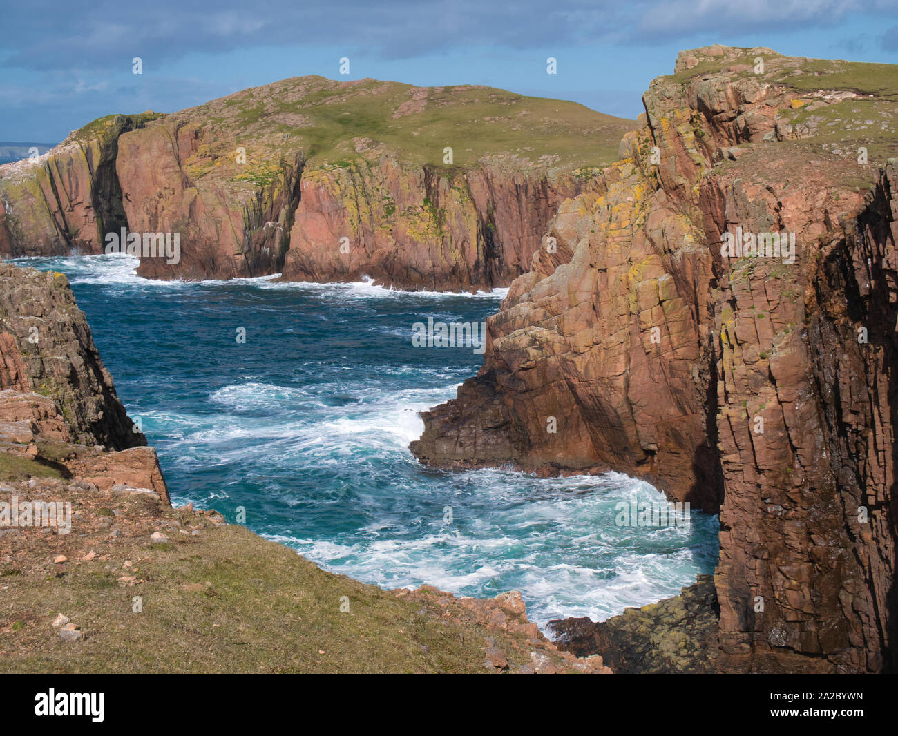 Scogliere sul mare vicino a North prosciutto sulla sindrome di Muckle Roe, Shetland, Regno Unito - il rock è la sindrome di Muckle Roe Intrusion - granito, granophyric - roccia ignea. Foto Stock