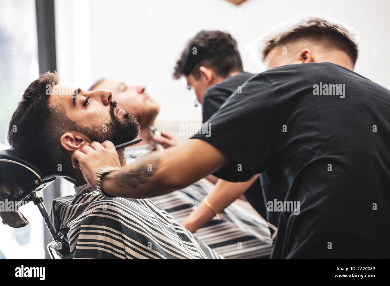 Imperia, Italia, 15/09/2019: Professional Barbieri che lavorano nel negozio nel centro della città di Imperia in Liguria, da il benvenuto ai clienti e tagliare le loro barbe Foto Stock