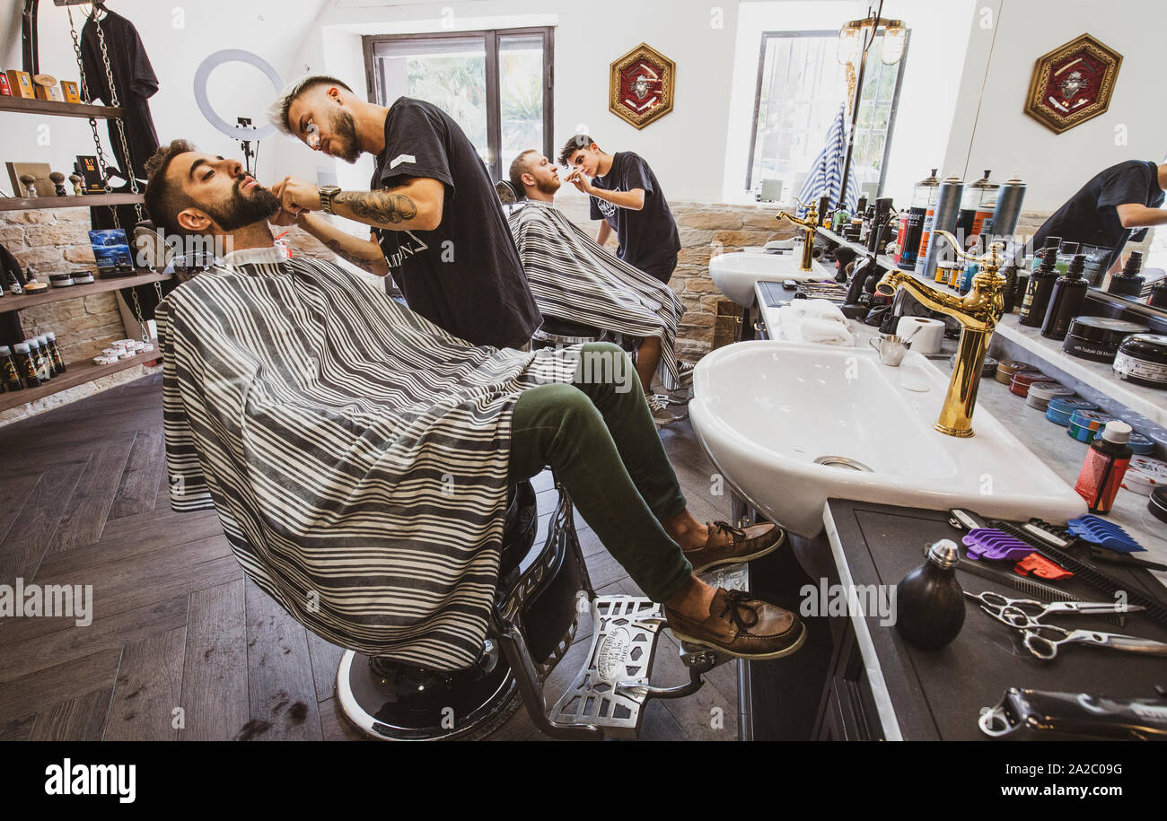 Imperia, Italia, 15/09/2019: Professional Barbieri che lavorano nel negozio nel centro della città di Imperia in Liguria, da il benvenuto ai clienti e tagliare le loro barbe Foto Stock