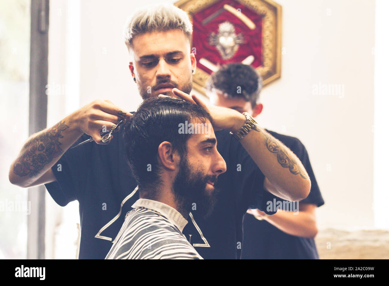 Imperia, Italia, 15/09/2019: Professional Barbieri che lavorano nel negozio nel centro della città di Imperia in Liguria, da il benvenuto ai clienti e tagliare le loro barbe Foto Stock