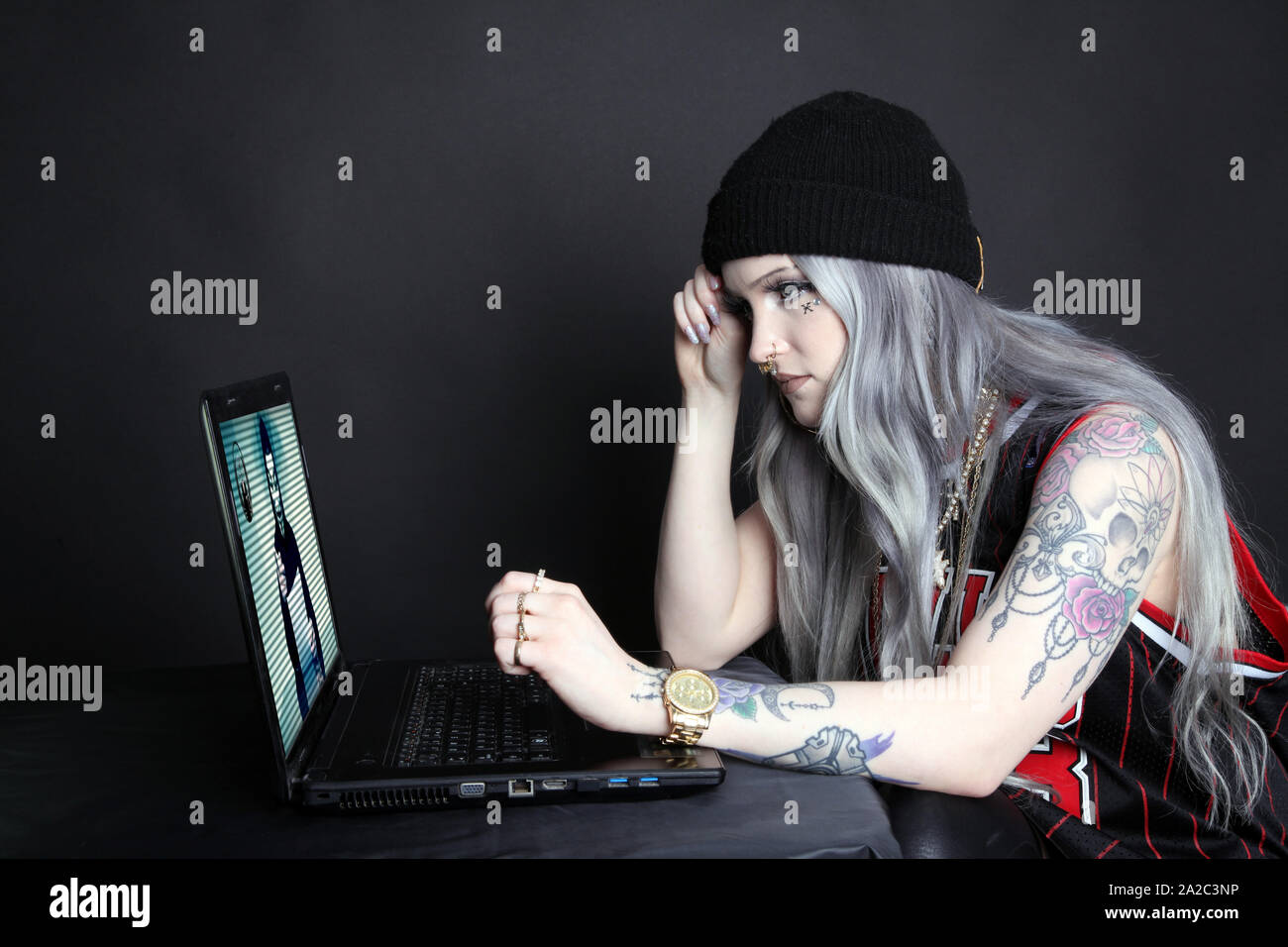 Vista laterale della donna millenario su laptop guardando anonimo gruppo di hacking video broadcast sullo schermo la chiave di basso 2019 Foto Stock