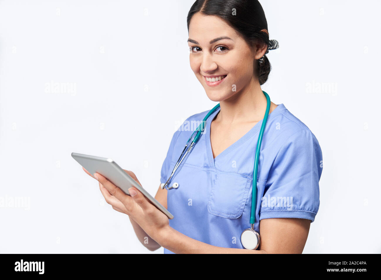 Ritratto di Studio shot di infermiera femmina indossando Scrubs utilizzando tavoletta digitale Foto Stock
