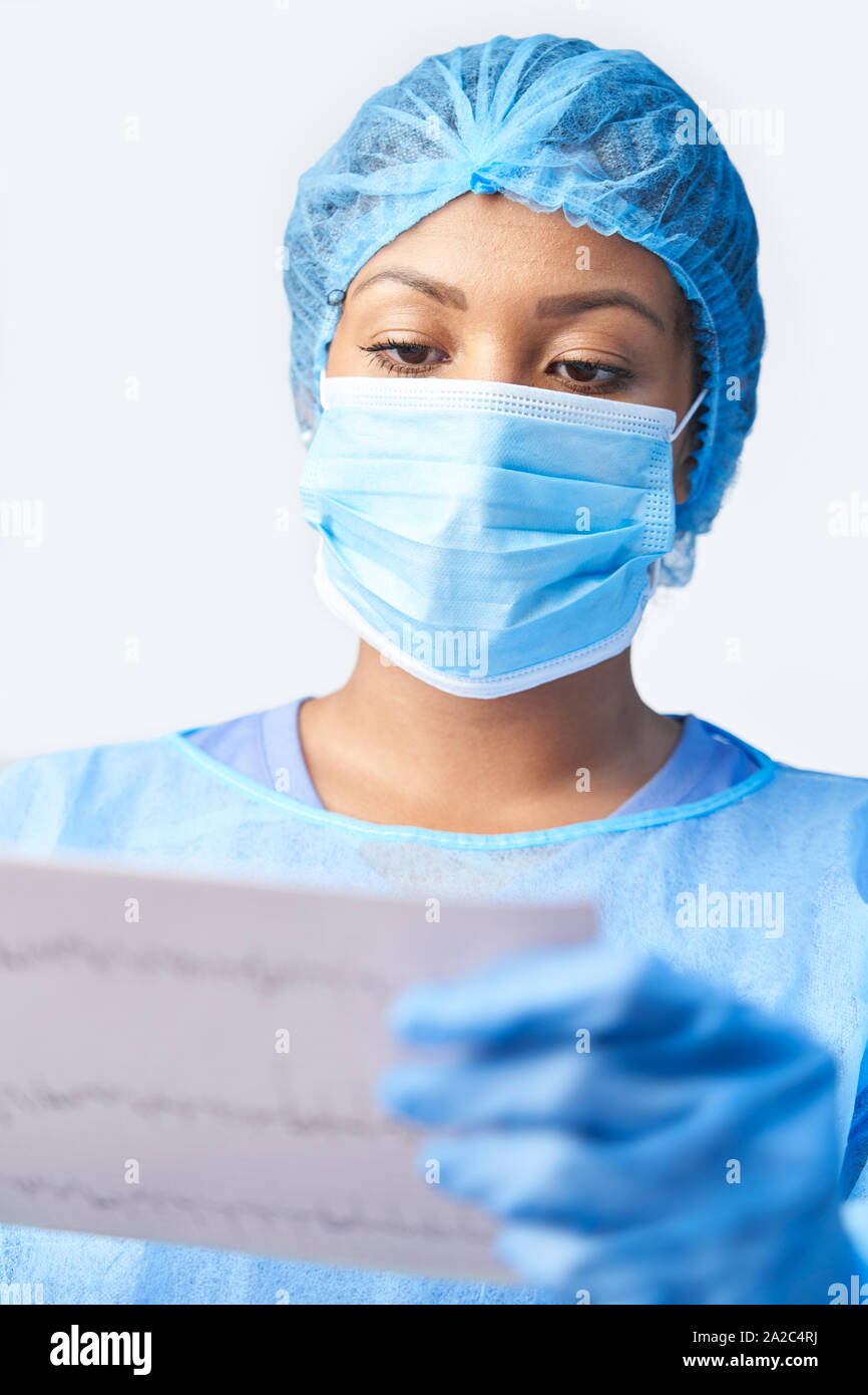 Chirurgo femmina indossando camice e maschera Holding Medical Stampare Foto Stock