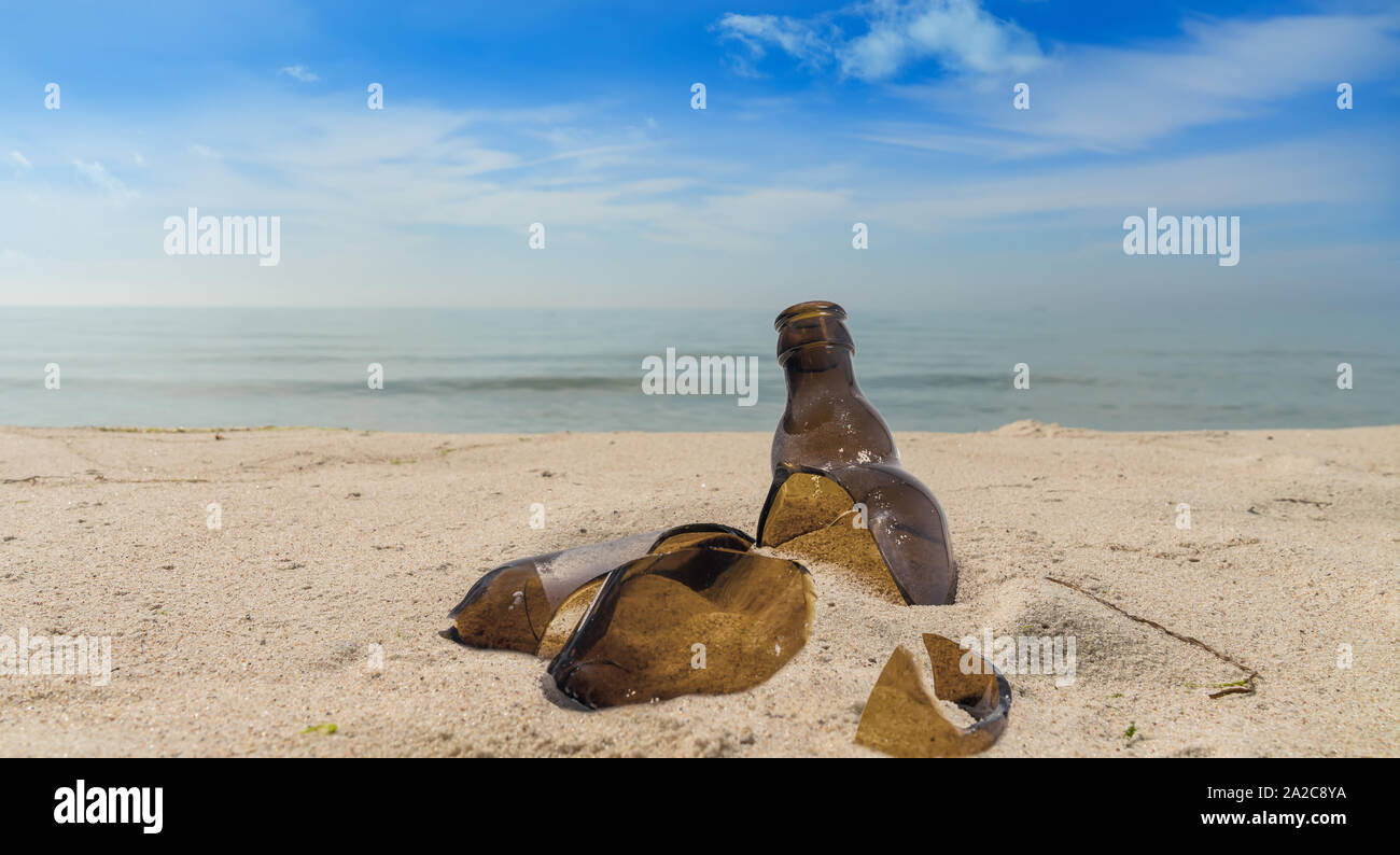 Inquinamento causato dalla rottura di un vaso di vetro che giace su di una spiaggia in sabbia Foto Stock