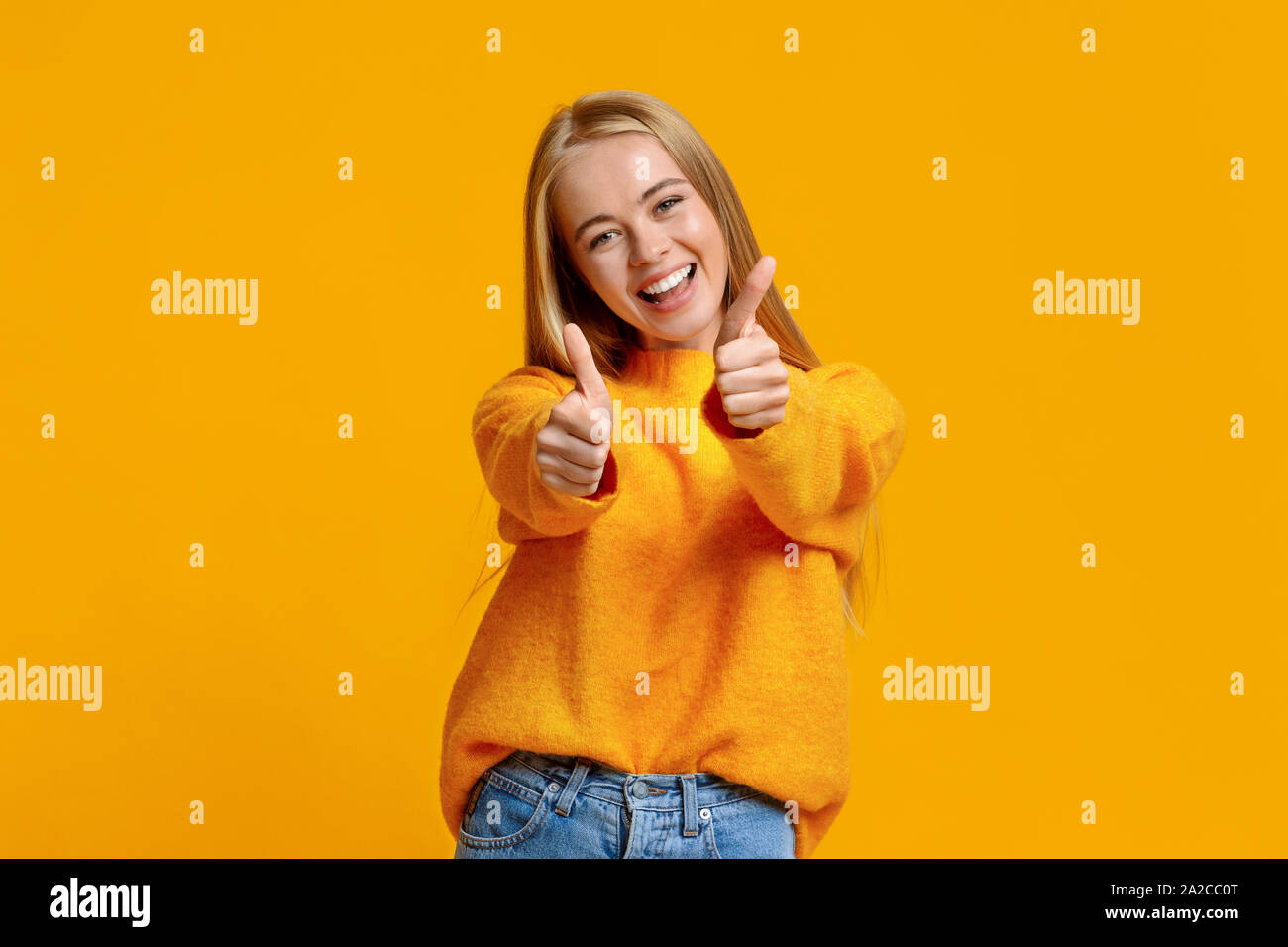 Gioiosa ragazza adolescente che mostra Thumbs up su sfondo arancione Foto Stock