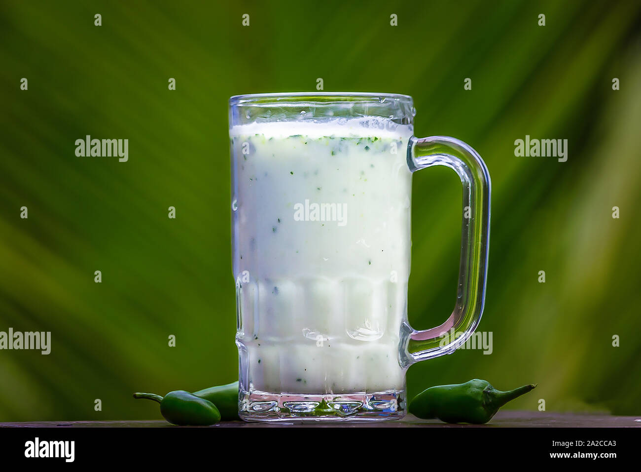 Burro latte su vetro con peperoncino verde isolato. Foto Stock