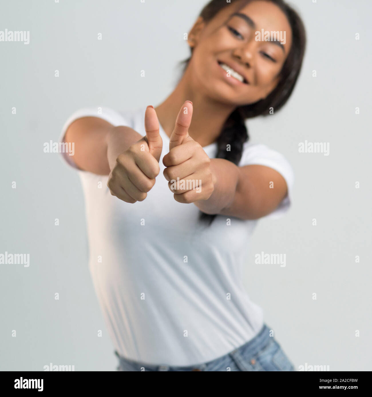 Overjoyed ragazza asiatica che mostra i pollici fino a studio Foto Stock