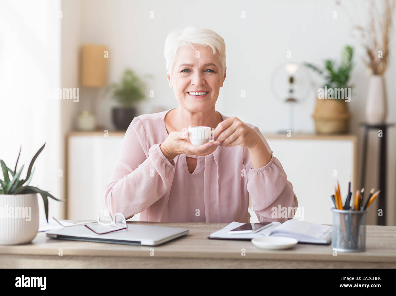 Tranquillo anziana signora avente pausa caffè durante il lavoro Foto Stock