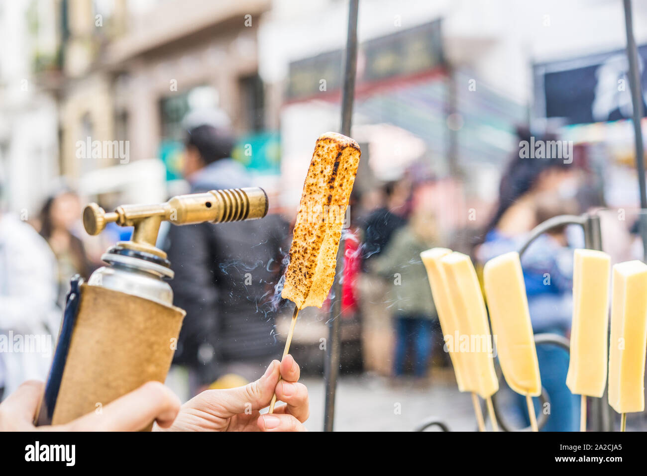 Un chef formaggio grill con un gas da cucina torcia presso un mercato alimentare. Foto Stock