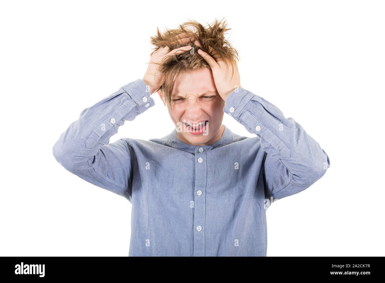 Frustrati ragazzo adolescente messing fino e tirando i capelli e le mani alla testa, guardando giù gridando e urlando, isolato su sfondo bianco con copia s Foto Stock