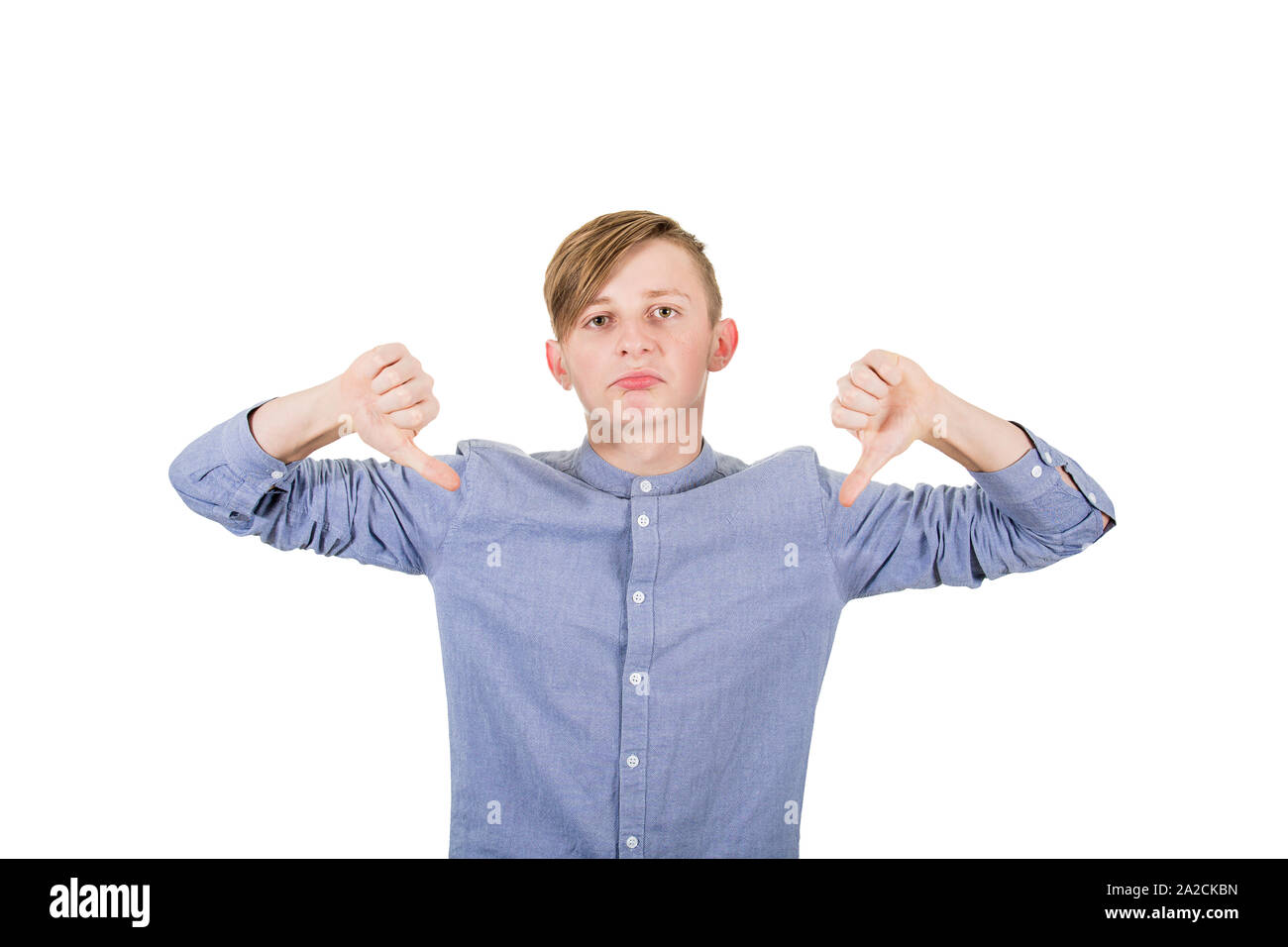 Orinato ragazzo adolescente che mostra entrambi i pollici giù, gesto negativo cattivo e feedback, guardando alla telecamera isolata su sfondo bianco. Foto Stock