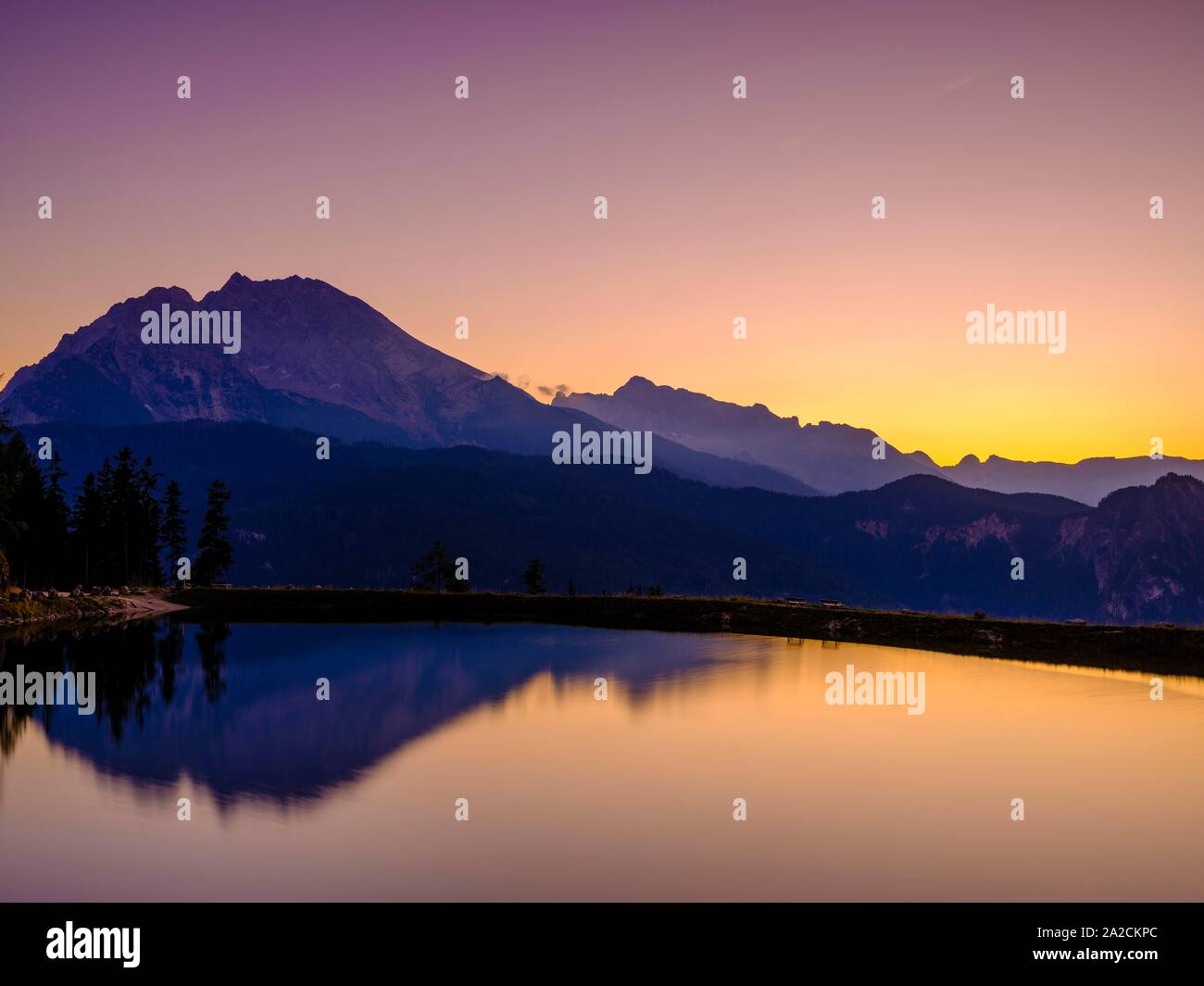 Sagome di montagna si riflette in un'artificiale lago di montagna al tramonto, Watzmann, Hochkalter Berchtesgaden Alpi, Parco Nazionale di Berchtesgaden Foto Stock