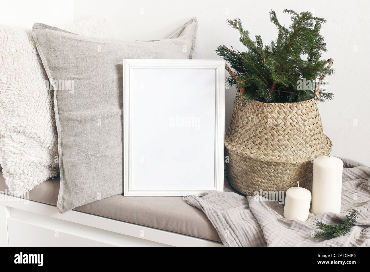 Vuoto bianco telaio in legno mockup con albero di Natale, candele, biancheria cuscini e plaid sul banco di bianco. Poster design di prodotto. Scandinavian home de Foto Stock