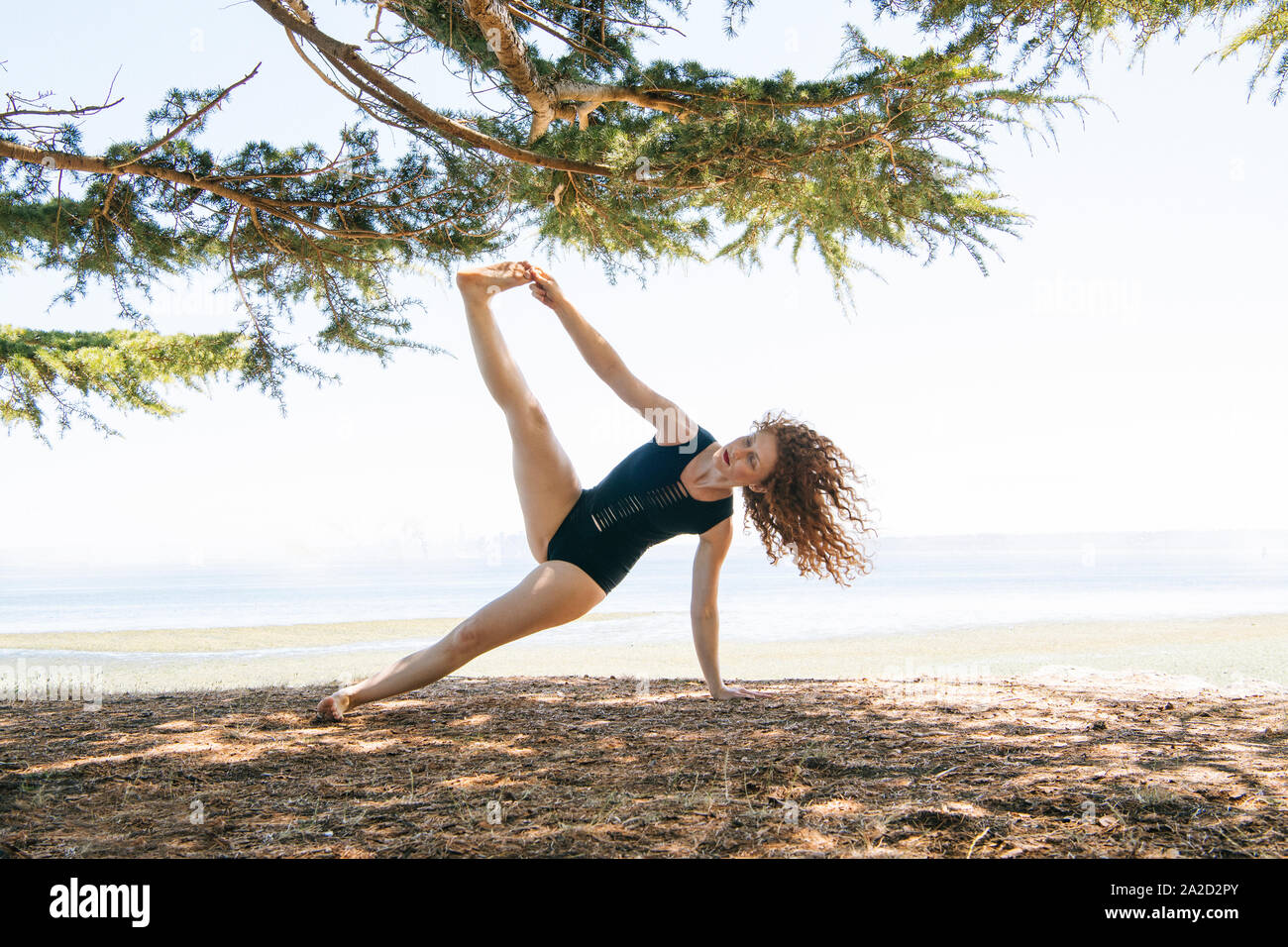 Donna fare yoga sulla riva del mare, Bainbridge Island, nello Stato di Washington, USA Foto Stock