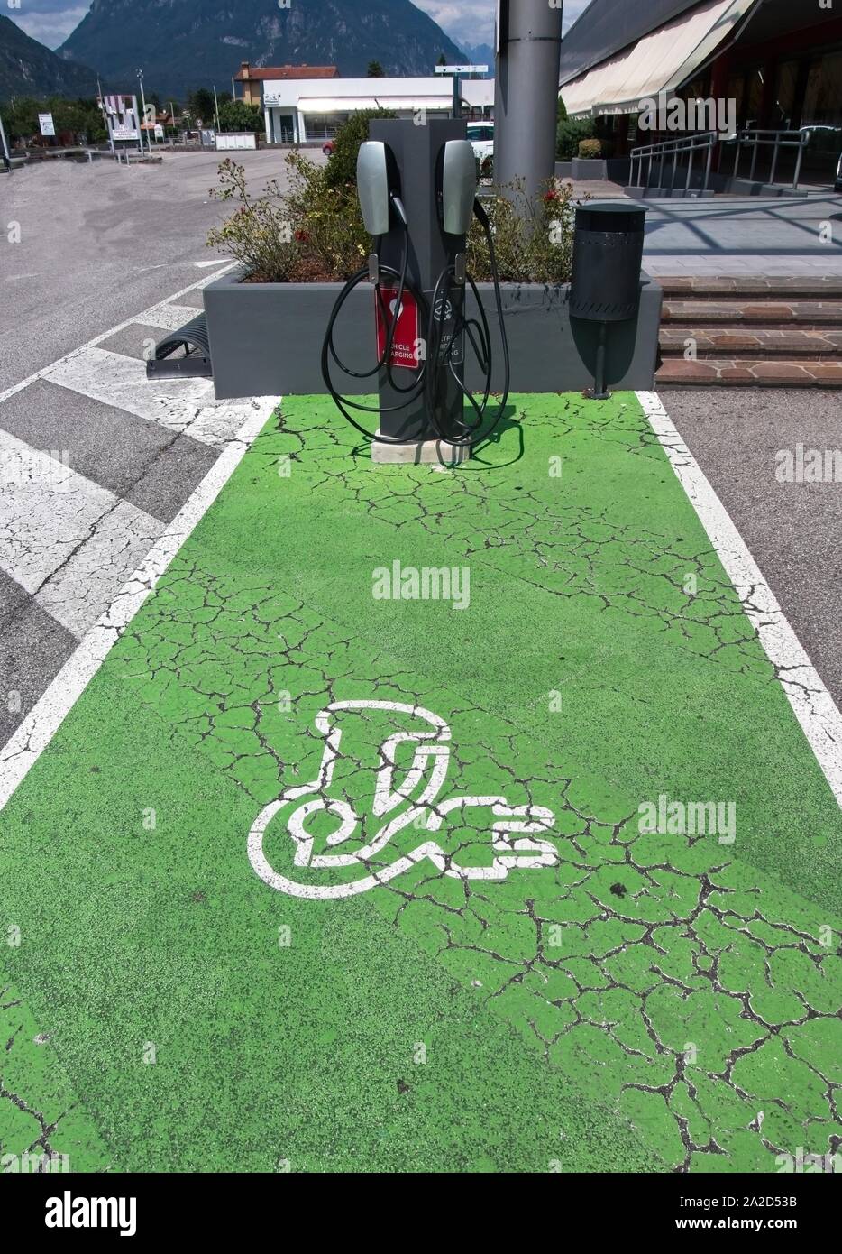 Il veicolo elettrico (VE) stazione di carica posto parcheggio con icona testo su invecchiamento dipinte di verde marciapiede. Foto Stock