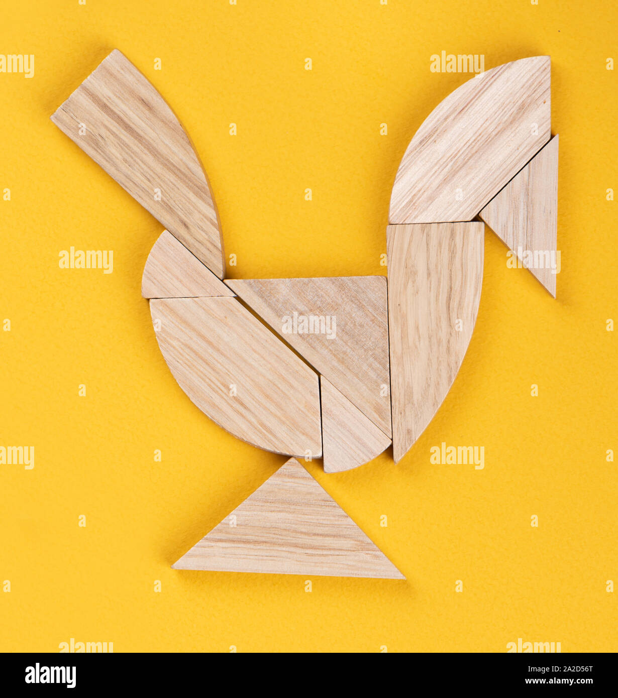 Un gallo figura è assemblato da pezzi di un puzzle tangram gioco su uno sfondo giallo. Concetto di puzzle. Foto Stock
