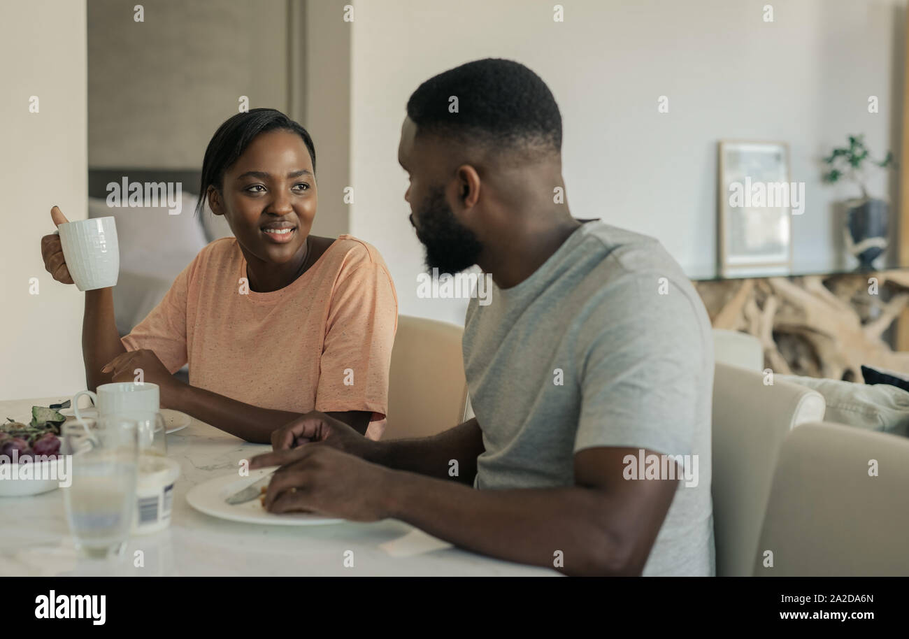 Sorridente giovane americano africano giovane gustando la prima colazione insieme a casa Foto Stock